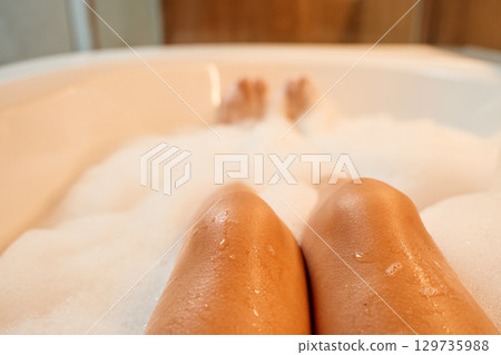 Woman relaxing in bath with foam in modern bathroom Woman relaxing in bath with foam in modern bathroom 129735988