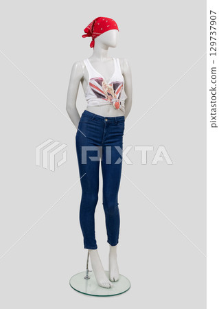 Full-length female mannequin dressed in slim jeans, T-shirt and red bandana on light gray background, front view. 129737907