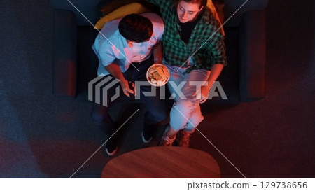 Top view of father and mother watch TV together while eating snack. Convocation. 129738656