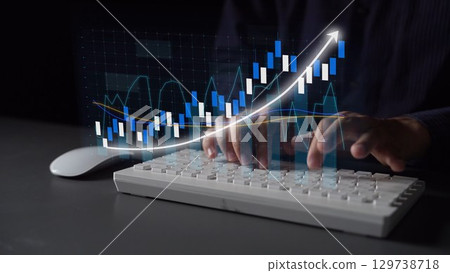 Hands Typing on Keyboard with Stock Market Data Visualization in Background Showing Increasing Financial Growth and Trends in Dark Environment Copula 129738718