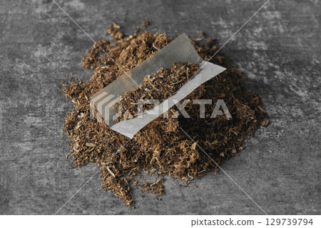 Tobacco leaves arranged for rolling cigarettes on a gray background 129739794