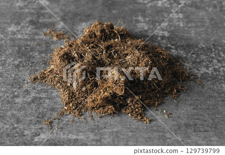 Dry tobacco leaves piled on a gray surface 129739799