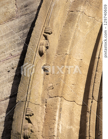 Carved face peeking from the stone at entrance to Abbey Church of Sainte-Foy in Conques, France Carved face peeking from the stone at entrance to Abbey Church of Sainte-Foy in Conques, France 129740609