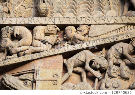Stone carvings depicting Hell on entrance of Abbey Church of Sainte-Foy in Conques, France 129740625