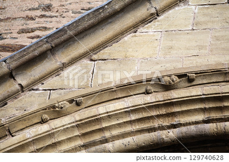 Carved face peeking from the stone at entrance to Abbey Church of Sainte-Foy in Conques, France Carved face peeking from the stone at entrance to Abbey Church of Sainte-Foy in Conques, France 129740628