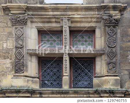 Historic window in Sarlat-la-Caneda, France, showcasing intricate stone carvings and stained glass 129740755
