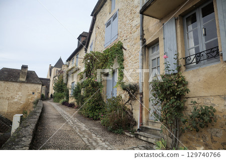 Stone houses nestled along a quiet pathway in Beynac-et-Cazenac village, France 129740766
