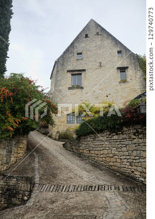 Stone houses nestled along a quiet pathway in Beynac-et-Cazenac village, France 129740773