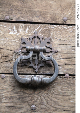 Old door knocker on a wooden door 129740775