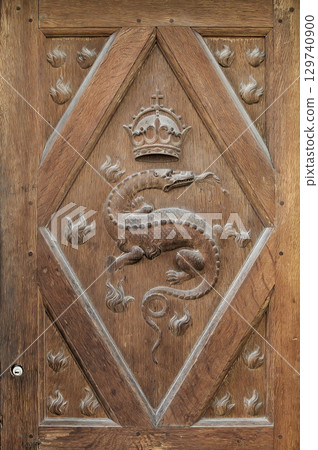 Intricate wooden door design featuring a carved dragon and crown at Chambord Castle in France 129740900
