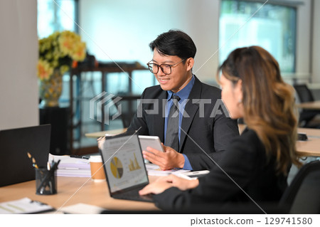 Businessman discussing financial reports with a colleague during a meeting in a modern office Businessman discussing financial reports with a colleague during a meeting in a modern office 129741580
