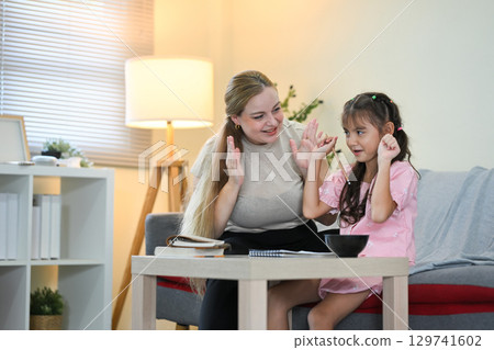 Happy mother cheering and encouraging her daughter while studying at home Happy mother cheering and encouraging her daughter while studying at home 129741602
