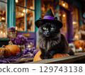 Black cat in a witch hat sitting on a Halloween pumpkin 129743138