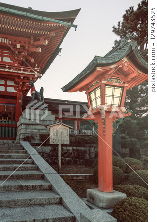 Vintage toned lantern near shrine gate with Shinto fox statue 129743525