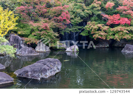 Japanese garden pond with autumn trees and waterfall scene 129743544
