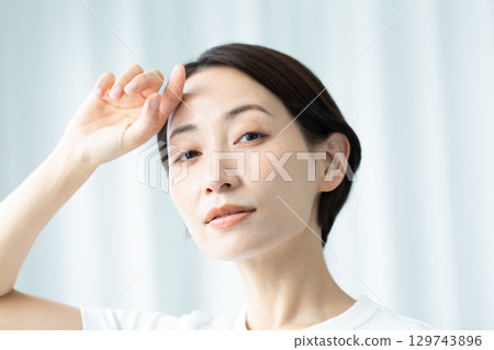 一個透明的女人，她的手放在額頭上，在光線下，美麗的皮膚，臉朝上，正面 129743896