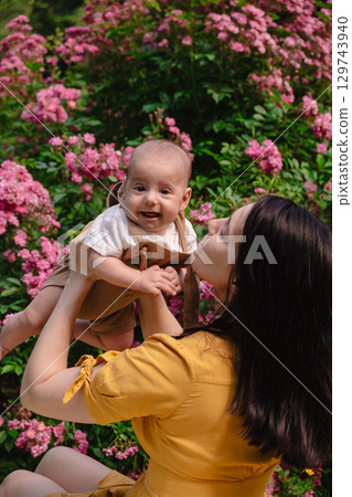Joyful Mother and Baby in Blooming Garden Joyful Mother and Baby in Blooming Garden 129743940