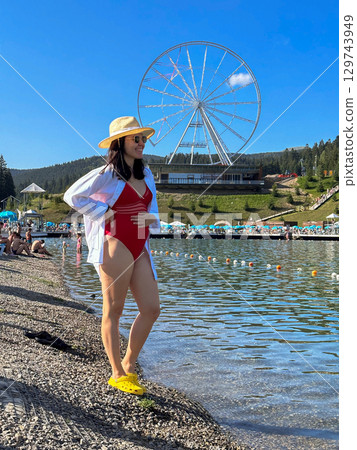 Woman at beach with ferris wheel 129743949