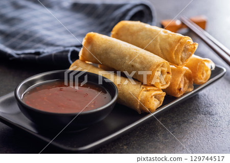 Fried spring rolls and sweet and sour sauce on wooden table. 129744517