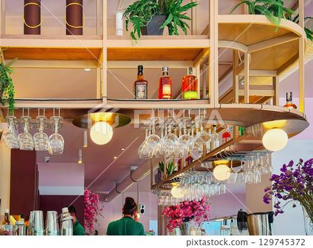 Modern bar interior with glassware, bottles and ambient lighting in stylish warm tones. Concept of bar interior, contemporary lifestyle 129745372