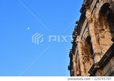 Nimes Amphitheatre at dawn with the moon visible and a clear summer sky (France / Photographed on August 13, 2025) 129745797