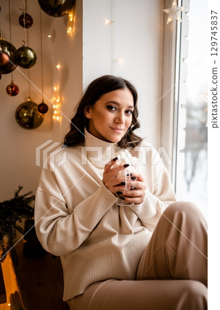 Woman Relaxing Near Window Holding Hot Drink 129745837