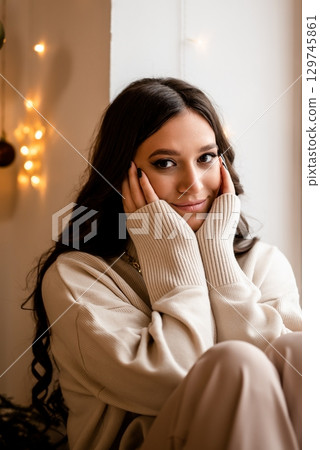 Cozy Woman Relaxing by the Window with a Soft Smile 129745861