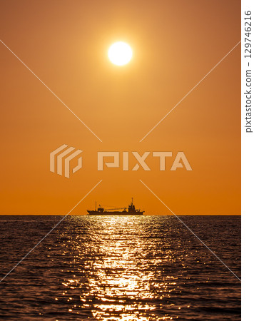 A summer sunset over the sea off Tsunoshima and the silhouette of a ship (Yamaguchi, August) 129746216