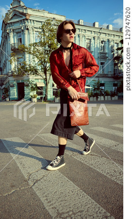 Stylish young man in red shirt and black denim shorts crossing urban street Stylish young man in red shirt and black denim shorts crossing urban street 129747620