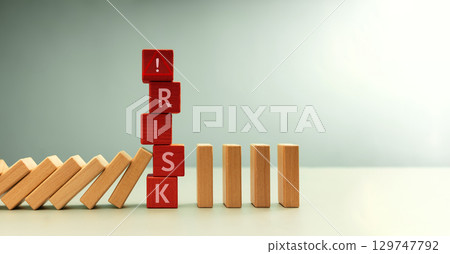 Row of falling dominos halted by red blocks spelling RISK. risk management, crisis prevention, and financial protection 129747792