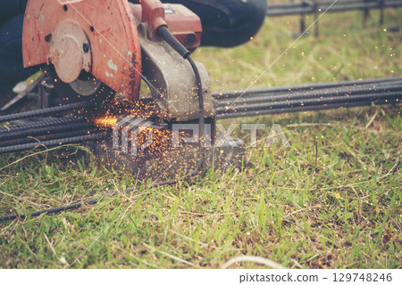 Construction Worker hands using Welding machinery iron metal sparking. Men hands wear protective glove Hot flame metal work cutting fire iron workshop. Locksmith use Welding machine cut metal process 129748246