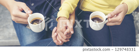 Banner Asian Business people smiling Relax holding cup of coffee in modern city. Couple lover enjoy drinking takeaway hot coffee together. Young Business people holding cup of coffee with copy space 129748331