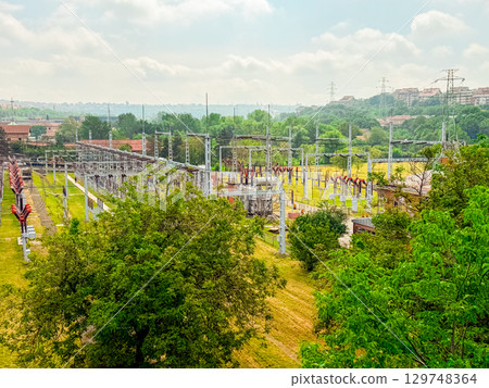 High-voltage power substation in a green landscape. Energy infrastructure, electricity distribution, and technology integration in modern urban planning. High-voltage power substation in a green landscape. Energy infrastructure, electricity distribution, and technology integration in modern urban planning. 129748364