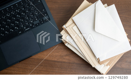 一台筆記型電腦和一堆信封 一台筆記型電腦和一堆信封 129749280