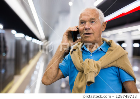 Old man with smartphone in subway station 129749718