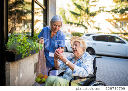 Home caregiver assisting older woman during grocery run 129750709