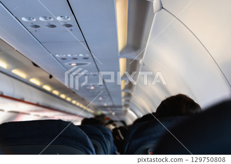 Inside the passenger plane cabin with people. Inside the passenger plane cabin with people. 129750808