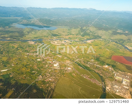 Aerial view of lake and farmlands near mountain range. Water resources, agricultural development, and diverse natural topography. 129751460