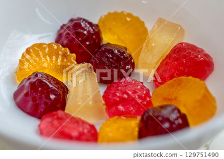 Assorted fruit jelly candies in various shapes and colors are displayed in close-up shot. The image captures the vibrant colors and textures of deliciously sweet treats Assorted fruit jelly candies in various shapes and colors are displayed in close-up shot. The image captures the vibrant colors and textures of deliciously sweet treats 129751490