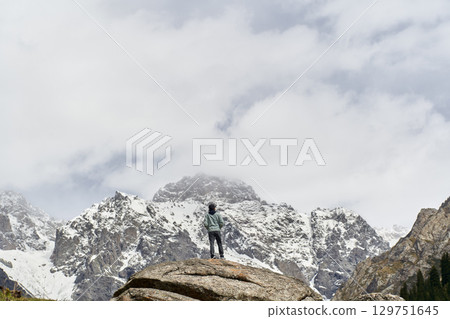 asian man standing on top of rock looking at peak of snow mountain asian man standing on top of rock looking at peak of snow mountain 129751645