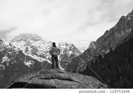 asian man standing on top of rock looking at peak of snow mountain 129751646