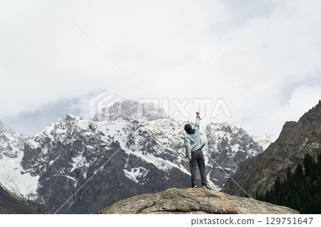 asian man standing on top of rock looking at peak of snow mountain asian man standing on top of rock looking at peak of snow mountain 129751647