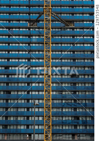 tower crane attached to the wall of a blue building, construction site tower crane attached to the wall of a blue building, construction site 129753548