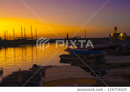 Photo of the lighthouse and ships in Kyrenia harbor at sunset in the Turkish Republic of Northern Cyprus Photo of the lighthouse and ships in Kyrenia harbor at sunset in the Turkish Republic of Northern Cyprus 129754020