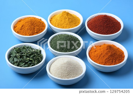 Spice mix in bowls with herbs on blue backdrop. Bold layout for cooking or health concepts. Perfect for organic or kitchen projects. 129754205