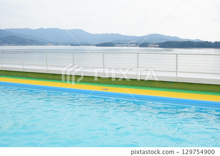 A summer view of the outdoor pool and lake. A vibrant view of blue and yellow. A summer view of the outdoor pool and lake. A vibrant view of blue and yellow. 129754900