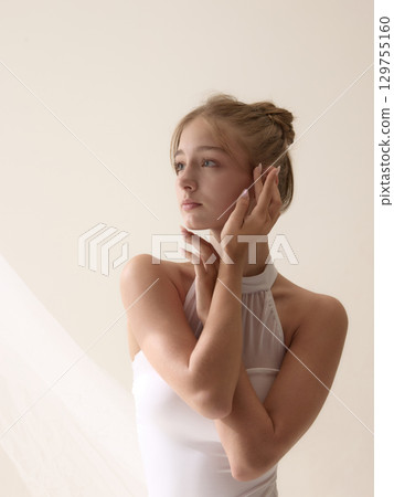 The art of being. Elegant young ballerina touching face with serene expression 129755160