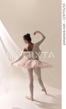 Ballet dancer in pink tutu performing graceful movement 129755254