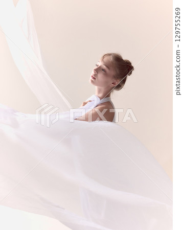 Portrait of young ballerina with flowing white fabric in soft light 129755269