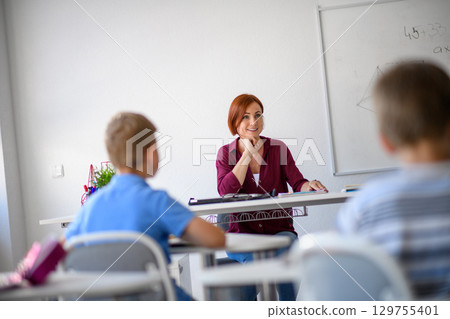 Teacher talking with children in primary class. 129755401